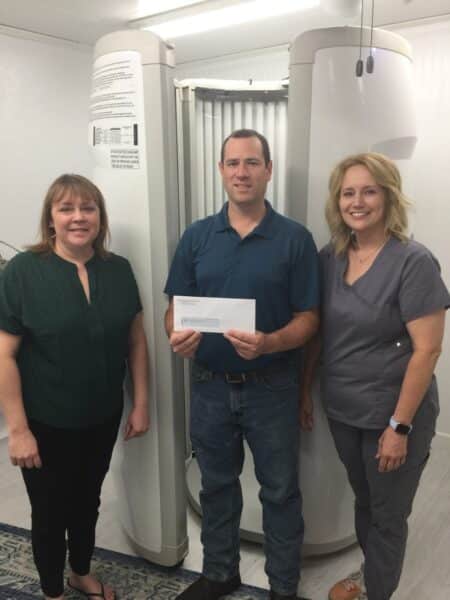 Three people posing with an envelope in a clinic