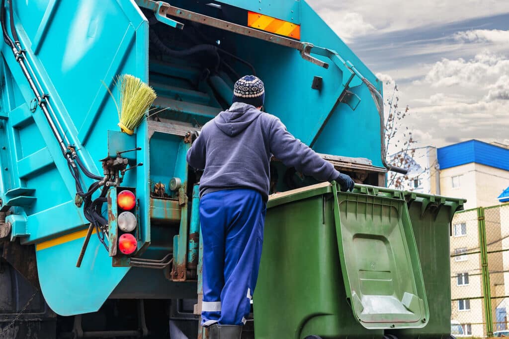 Worker operating a blue garbage truck